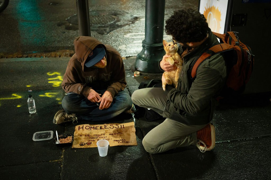 Un mendiant qui parle avec un passant tenant son chat